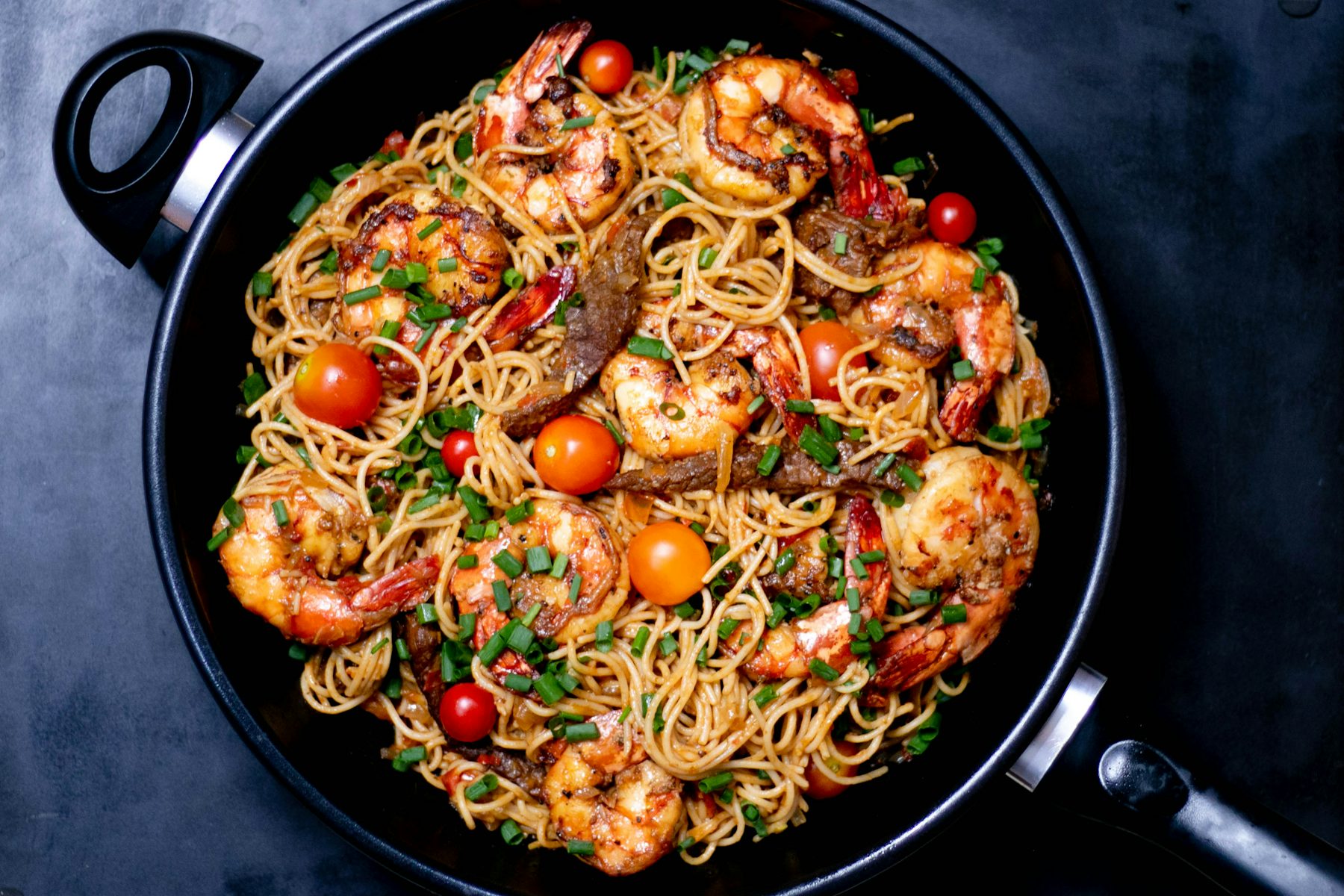 Poêle de linguine aux gambas et tomates cerises, sur une table sombre